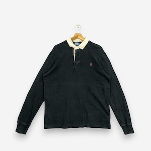 May include: A long-sleeve black rugby shirt featuring a cream-colored collar, a button-up placket, and a small red embroidered logo on the left chest. The shirt includes a blue interior neck label with the text Polo by Ralph Lauren.