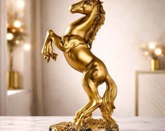 Op de afbeelding: Een gouden paardenbeeld dat zich opricht. Het paard heeft een vloeiende manen en staart en staat op een getextureerde basis. Het beeld is een decoratief item.