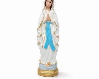Op de afbeelding: Een wit beeld van een religieuze figuur met een blauwe sjerp en gouden accenten. De figuur staat met gevouwen handen in gebed. Een gouden rozenkrans hangt om de nek. De basis is goudkleurig met een blauw en wit ontwerp.