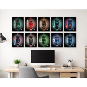 以下が含まれることがあります： 10枚の額装されたF1レーシングカーのプリントのコレクション。それぞれ異なるチームの車両が描かれています。プリントは2列に配置され、車の上面図が黒い背景に表示されています。アートワークは、コンピューターのある机の上に表示されています。