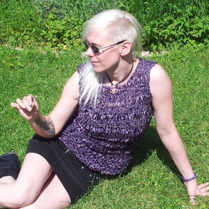 May include: A woman wearing a purple crochet top and black skirt sits on a grassy lawn. She is wearing sunglasses and has a shaved head. The text "Gothic Chameleon on Etsy" is visible in the lower right corner of the image.