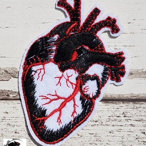 May include: Black and red embroidered anatomical heart patch. The heart is outlined in black with red veins and arteries.