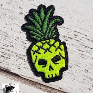 May include: Green embroidered iron-on patch of a pineapple skull with black outlines.