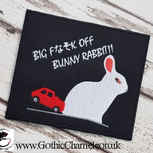 May include: Black embroidered patch with white text that reads "BIG F*CK OFF BUNNY RABBIT!" and a white rabbit with red ears being run over by a red car.
