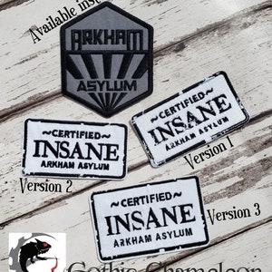 May include: Three different versions of a black and white embroidered patch that reads "~CERTIFIED~ INSANE ARKHAM ASYLUM". The patches are on a wooden background. The first version has a white background and black text. The second version has a black background and white text. The third version has a white background and black text.