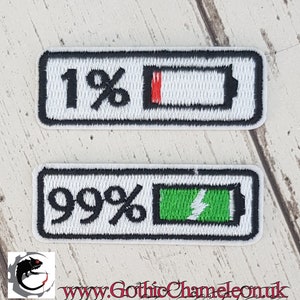 Op de afbeelding: Twee witte geborduurde strijkpatches met zwarte randen. De bovenste patch toont een batterijpictogram met 1% lading. De onderste patch toont een batterijpictogram met 99% lading.