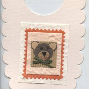 Tarjeta en forma de babero de bebé con diseño de oso de peluche
