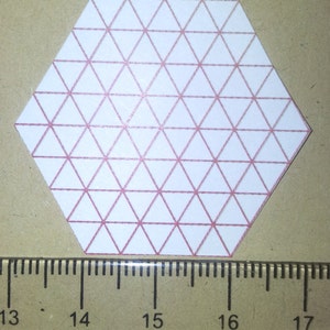 Peut inclure: Un papier blanc en forme d'hexagone avec un motif de grille de triangles roses. L'hexagone mesure environ 10 cm de large.