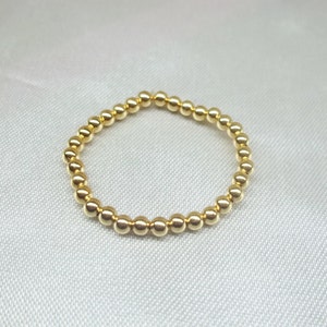 May include: A gold beaded ring with a simple design. The ring is made of small, round beads that are evenly spaced.