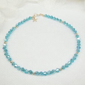 May include: A delicate blue crystal anklet with a gold starfish charm. The anklet is made of small, faceted crystals and is strung on a thin gold chain.