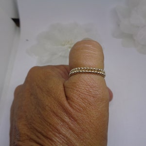 May include: A gold beaded ring with two rows of beads.