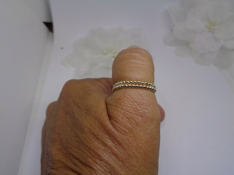 May include: A gold beaded ring with two rows of beads.