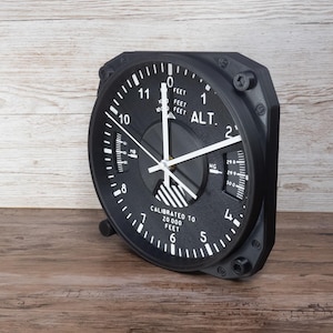 Pilot gift wall clock modeled after a Cessna aircraft cockpit altimeter. This aviation decor features realistic flight instrument details, a black bezel, and white dial lettering and clock hands.