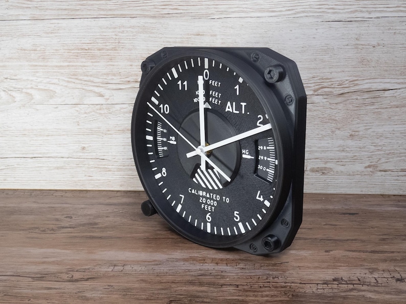 Pilot gift wall clock modeled after a Cessna aircraft cockpit altimeter. This aviation decor features realistic flight instrument details, a black bezel, and white dial lettering and clock hands.