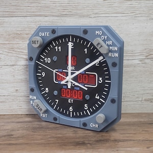 Pilot gift wall clock modeled after an Airbus aircraft cockpit chronometer. This aviation decor features realistic flight instrument details, a grey bezel, and digital time displays.
