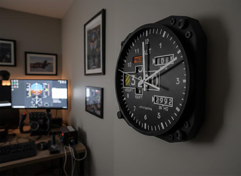 May include: Black aviation-themed wall clock with white numerals and hands. The clock face includes the text "ALT", "PNEU", "1013", "2992 IN HG", and "AVIATIONTIME". The clock is mounted on a gray wall.