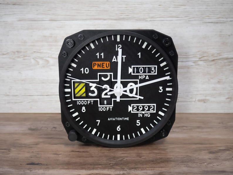 May include: Black aviation-themed clock with white numerals and hands. The clock face displays altitude and pressure readings, with the text "AVIATIONTIME" at the bottom. The clock is set to 3200 feet.