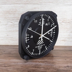 Pilot gift wall clock modeled after a Cessna aircraft cockpit altimeter. This aviation decor features realistic flight instrument details, a black bezel, and white dial lettering and clock hands.