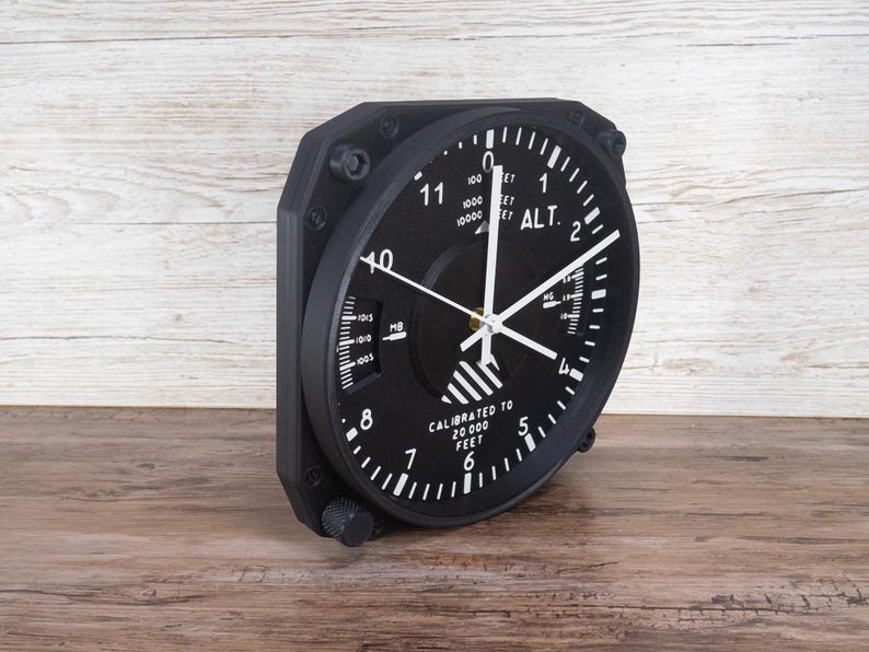 Pilot gift wall clock modeled after a Cessna aircraft cockpit altimeter. This aviation decor features realistic flight instrument details, a black bezel, and white dial lettering and clock hands.