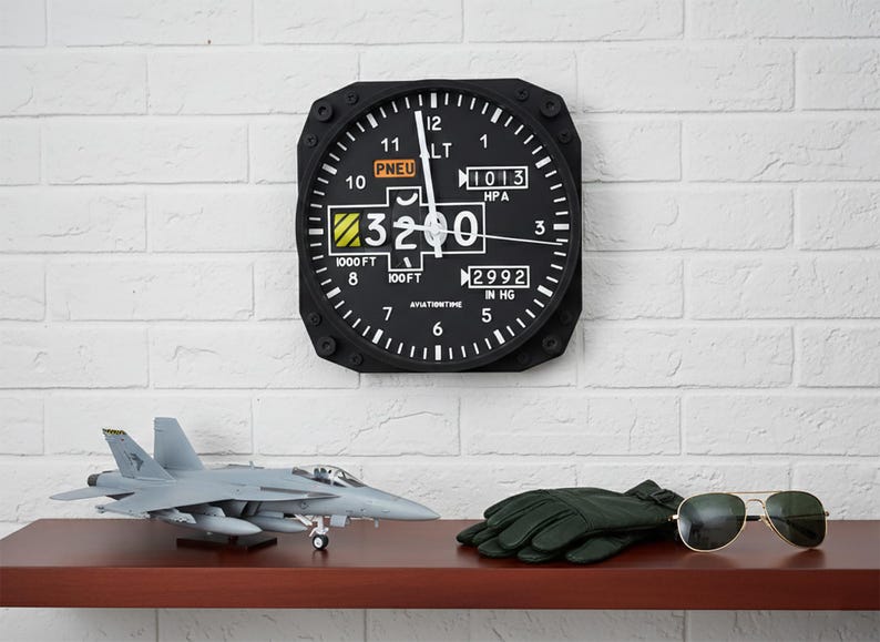 May include: Aviation-themed decor featuring a black altimeter clock, a model jet, green gloves, and aviator sunglasses. The clock displays numbers and markings, including "3200" and "1000 FT". The items are arranged on a dark brown shelf against a white brick wall.