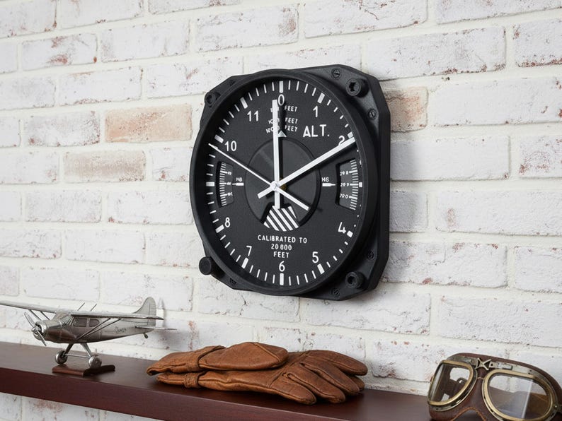Pilot gift wall clock modeled after a Cessna aircraft cockpit altimeter. This aviation decor features realistic flight instrument details, a black bezel, and white dial lettering and clock hands.