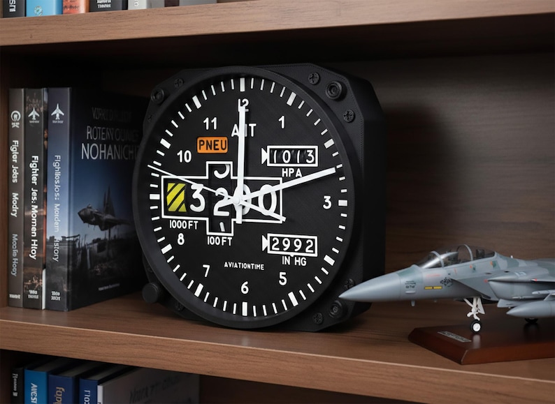 May include: Black aviation-themed clock with white markings and hands, displaying altitude and pressure readings. The clock is on a wooden shelf with model airplane and books.