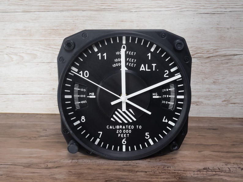 Pilot gift wall clock modeled after a Cessna aircraft cockpit altimeter. This aviation decor features realistic flight instrument details, a black bezel, and white dial lettering and clock hands.