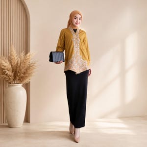 Puede incluir: Una túnica de color amarillo mostaza de manga larga con intrincados bordados florales blancos a lo largo de la tapeta y el dobladillo, combinada con una falda negra larga hasta el suelo, un pañuelo a juego y un pequeño bolso de mano negro.