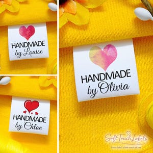 May include: White fabric labels with the text "HANDMADE" and a name below, featuring a heart design. The labels are on a yellow fabric background. The text "Soft Touch Labels" and "Every label, a little touch of love" are also visible.