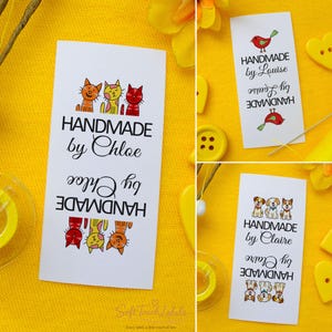 Könnte beinhalten: Weiße Stoffetiketten mit dem Text "HANDMADE by Chloe", mit Cartoon-Katzen-Illustrationen. Andere Etiketten sagen "HANDMADE by Louise" mit Vogelillustrationen und "HANDMADE by Claire" mit Hundeillustrationen.