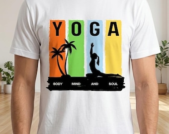 Puede incluir: Camiseta blanca con la palabra "YOGA" en letras mayúsculas negras, cada letra sobre una franja vertical de diferente color. Una silueta negra de una persona haciendo yoga y palmeras están debajo de la palabra "YOGA". Las palabras "BODY MIND AND SOUL" están debajo.
