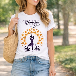 May include: White t-shirt with the word "Namaste" in a cursive font above a yoga pose silhouette within a sunburst design. The shirt is paired with denim shorts and a straw hat. A woven tote bag is carried over the shoulder.