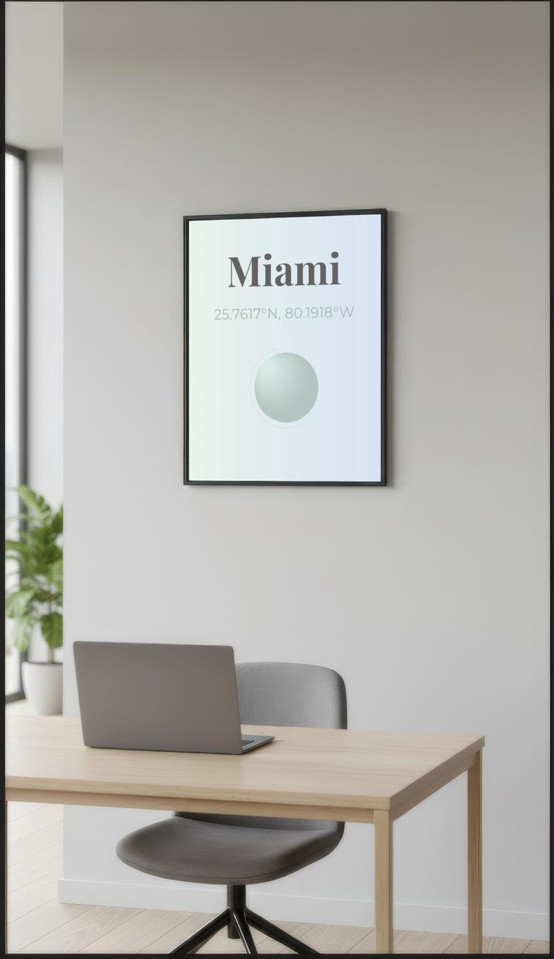 May include: A framed poster with the word "Miami" in bold, black text, along with coordinates. Below, a light green and blue gradient background features a white sphere. A laptop sits on a light wood desk with a gray chair.