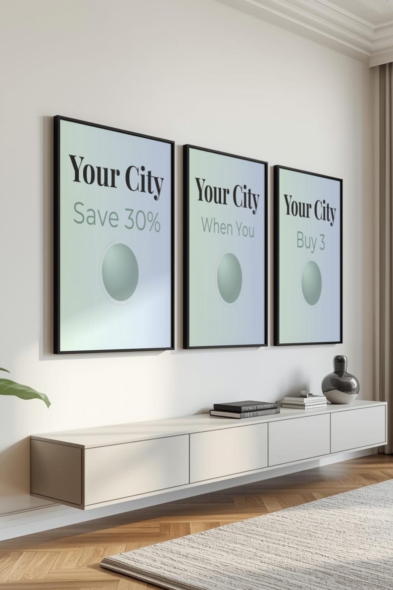 May include: Three framed posters with the text "Your City" in a bold font. Each poster has a different tagline: "Save 30%", "When You", and "Buy 3". Below, a white cabinet with books and a decorative vase.