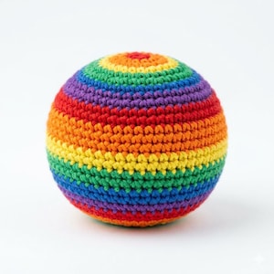 May include: A crocheted ball in a vibrant rainbow of colors, including red, orange, yellow, green, blue, and purple. The ball is round and appears to be handmade, with visible stitch details. The ball is a playful and colorful item.