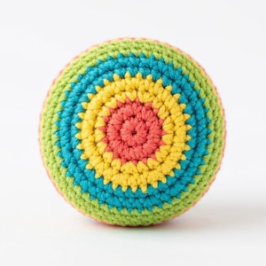 Peut inclure: Une balle crochetée à la main aux couleurs vives, avec des cercles concentriques rouges, jaunes, bleus et verts. La balle est ronde et semble être faite de fil doux. Idéale pour le jeu des enfants ou comme objet décoratif.