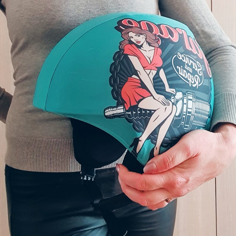 May include: A turquoise blue helmet cover with a pin-up girl illustration and the text "Repair and Service Garage".