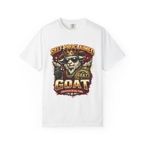 May include: White t-shirt featuring a graphic of a goat wearing sunglasses and a crown, with the text "SELF PROCLAIMED GOAT GREATEST OF ALL TIME". The goat is wearing a gold chain and holding up a finger.