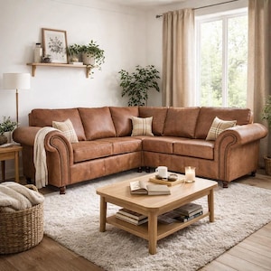 May include: A brown leather corner sofa with scrolled arms and stud detailing. The sofa is in a living room with a light rug, wooden coffee table, and cushions. The room has a warm, inviting atmosphere.