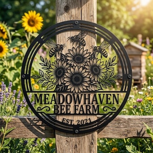 Könnte beinhalten: Ein rundes schwarzes Metallschild mit einem ausgeschnittenen Design aus drei Sonnenblumen und drei Bienen. Der Text MEADOWHAVEN BEE FARM ist in der Mitte zentriert, mit EST. 2021 darunter. Das Schild ist mit vier sichtbaren Schrauben befestigt.