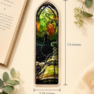 May include: A rectangular bookmark with a stained-glass design featuring an astronaut and a futuristic structure. The bookmark is 7.5 inches long and 2.25 inches wide. The design incorporates green, orange, and yellow hues, with a dark background.