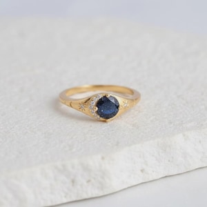 Peut inclure: Ensemble de trois mugs en céramique avec un glaçage moucheté de couleur crème. Chaque mug présente un motif peint à la main différent : une feuille bleue et verte, une fleur jaune et une baie rouge. Les mugs ont une forme simple et arrondie.