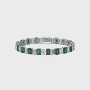 Può includere: Un bracciale in argento con pietre preziose verdi e bianche taglio smeraldo alternate. Il bracciale presenta pietre verdi taglio smeraldo e pietre bianche rettangolari, collegate da una catena e una chiusura in argento.