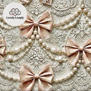 以下が含まれることがあります： 浮き彫りの花柄とレース模様が施された、装飾的で質感のある白い表面のクローズアップ。 金色のアクセントと白い真珠のストリングが付いた、ブラッシュピンクのリボンが特徴です。 テキスト「Lovely Looply」は白い円の中にあります。