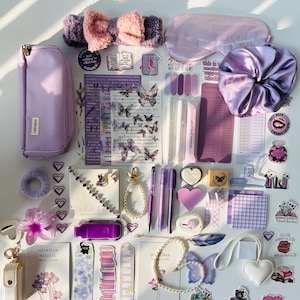 Puede incluir: Un surtido de artículos de papelería y accesorios morados y lavanda, que incluyen un estuche, bolígrafos, pegatinas, una diadema, una máscara para dormir, una goma para el pelo y artículos decorativos. Los artículos están dispuestos sobre una superficie blanca.