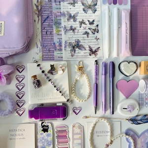 May include: An assortment of purple stationery and accessories, including pens, bookmarks, stickers, and a pencil case. The items feature butterfly and floral designs, with a cohesive aesthetic. A purple USB drive and a bracelet are also visible.
