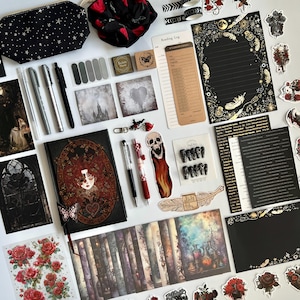 May include: An assortment of gothic-themed stationery and accessories, including a journal, pens, stickers, and washi tape. The items feature dark colors, roses, skulls, and celestial designs. A black pouch with white stars is also included.