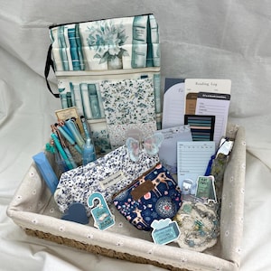 Peut inclure: Un panier tissé rectangulaire contenant une collection sur le thème des livres, incluant une trousse à motif de bibliothèque, une trousse à crayons fleurie, une petite pochette bleu marine à motif de cerf, des stylos, un carnet de lecture et des autocollants.