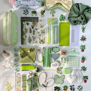 May include: A collection of green and white stationery and accessories, such as pens, stickers, a pencil case, a headband, and a sleep mask. Decorative elements include butterflies, plants, and heart shapes.