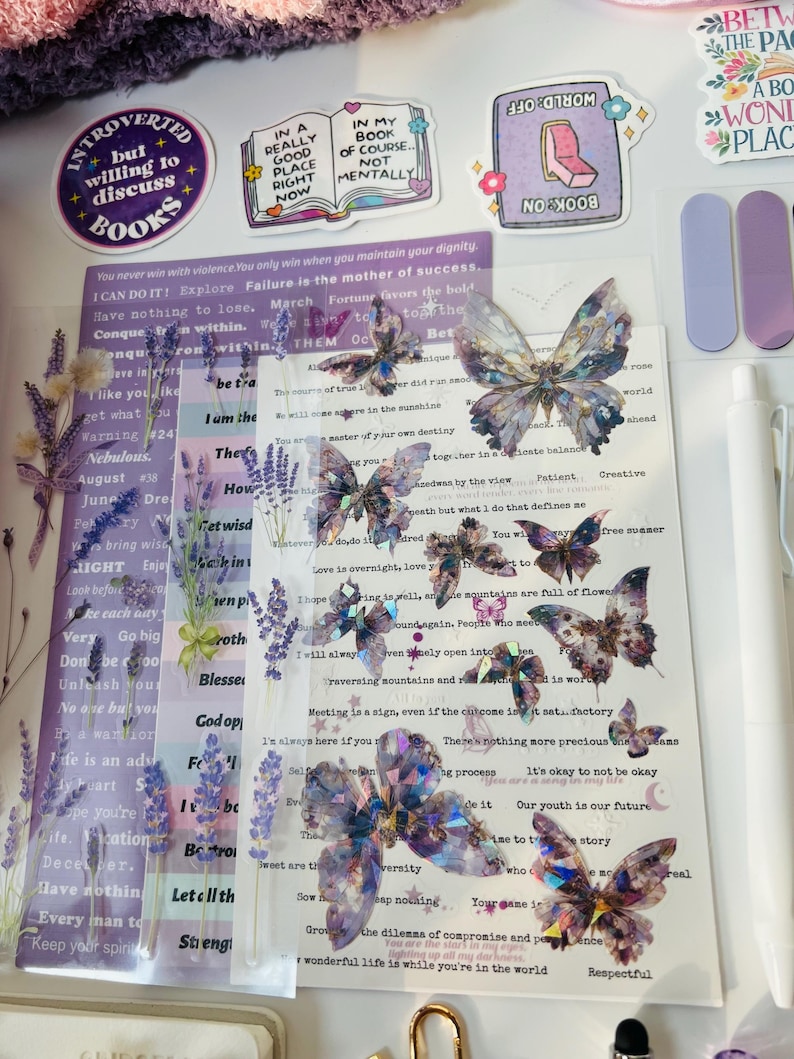 May include: A collection of decorative stickers and embellishments, including butterfly and floral designs, along with inspirational quotes. The color palette includes purple, white, and iridescent elements, perfect for scrapbooking or journaling.